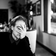 A photo of a man sitting at a dinner table, covering his face with one hand