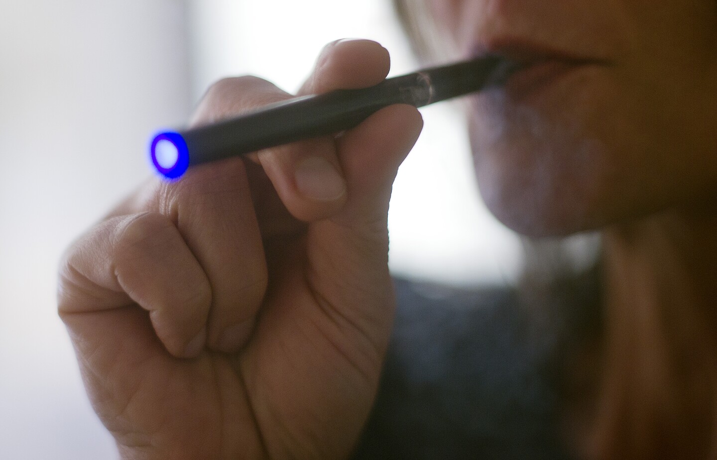 This September 25, 2013 photo illustration taken in Washington, DC, shows a woman smoking an 'Blu' e-cigarette. In Los Angeles Wednesday, the city council voted unanimously to regulate them much the same way as tobacco products.