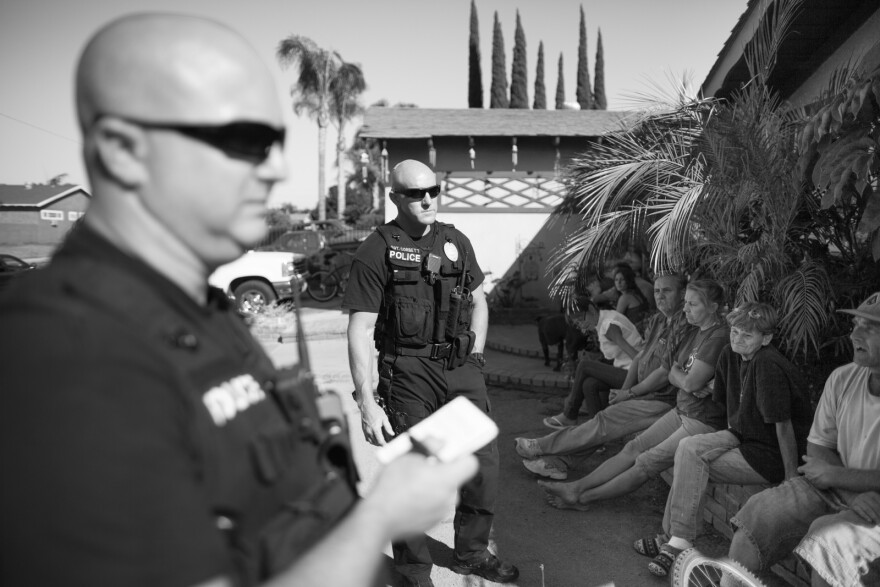Sergeant Corbett talks with residents at a home in Corona, Calif. where narcotics and other illegal items were found.