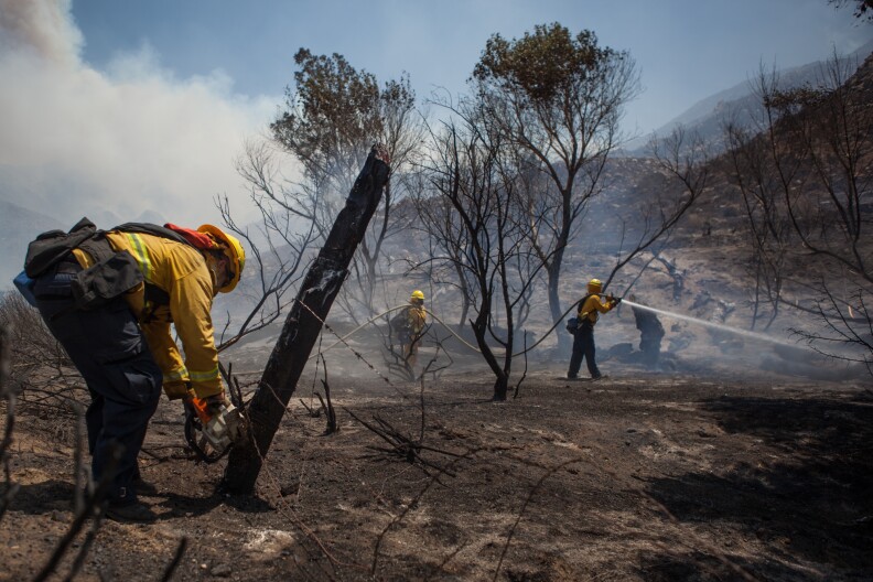 Hayden Harshman of the Oceanside Fire Department chops down a fencepost near homes that are threatened by the Silver Fire.