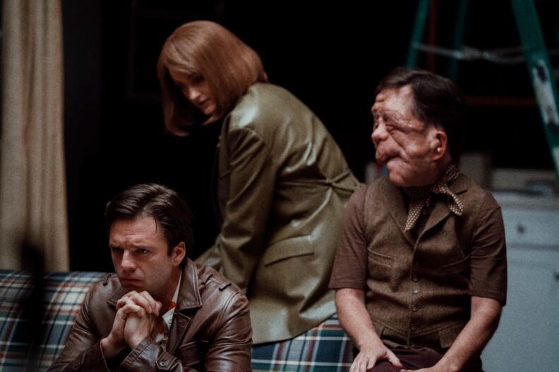 Two men sit on a couch. A woman leans in behind them.