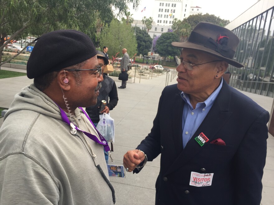 Black Lives Matter activist Greg Akili, right, claims he was wrongfully arrested by the LAPD during a police commission meeting.