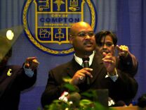 F364596 03: Compton Mayor Omar Bradley, who professes to fear for his life at the hands of some Compton Police officers, points fingers as he gives his annual "state of the city" address February 15, 2000 in Compton, California. Bradley had arrived to the previous week's City Counsel meeting with four civilian bodyguards to protect him from police. The Compton Police Officers Association has called for Bradley's recall and he has accused the police of corruption. (Photo by David McNew)