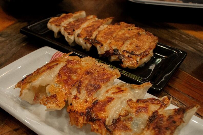 Crispy gyoza served on a black plate and a white plate.