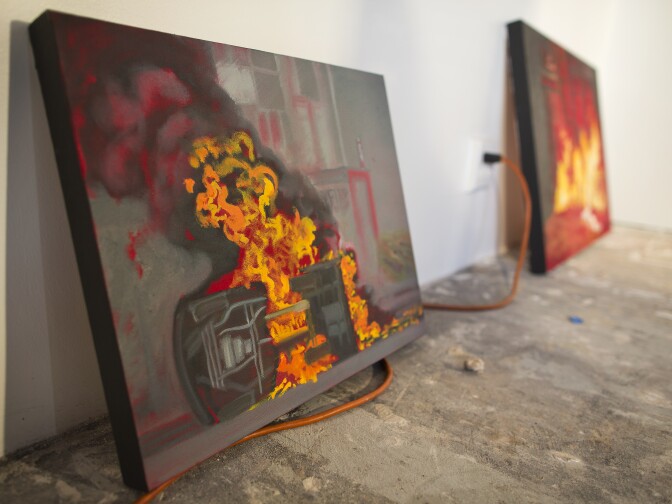A painting of an overturned car engulfed in flames is part of Sandy Rodriguez's series of recent protests in Mexico City after 43 local students went missing.