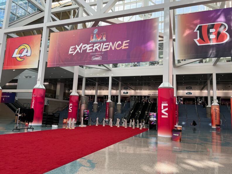 The entrance to the NFL Super Bowl Experience at the Los Angeles Convention Center on February 4, 2022 includes a long red carpet, pillars with the Roman numeral LVI, a large sign that says Super Bowl Experience, flanked by the logos of the Los Angeles Rams and the Cincinnati Bengals.