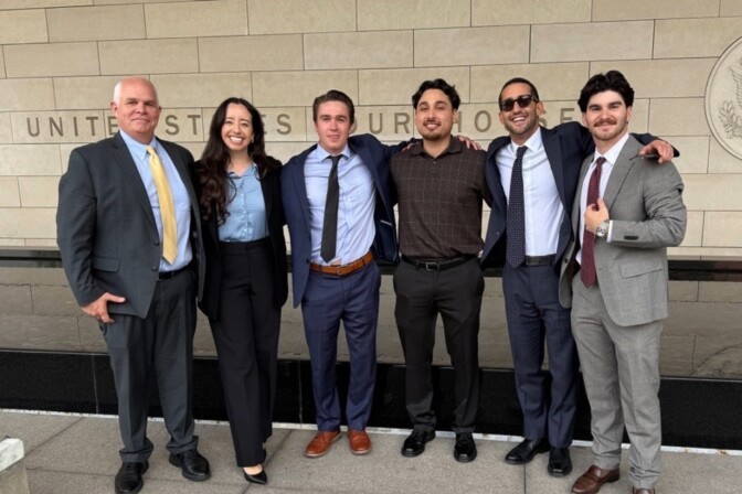 Six people stand in front of a federal courthouse in downtown Los Angeles.