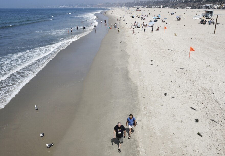 People walk on beach in an overhead shot.