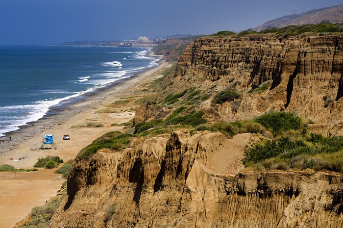 Ocean with gentle waves cresting on the left, and beautiful cliffs on the right.