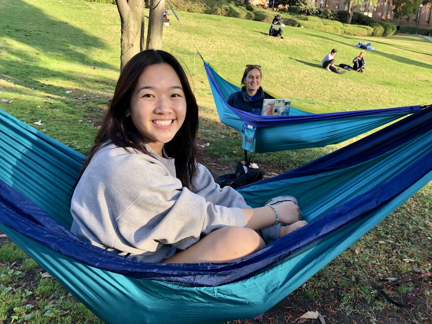 Two women sit in two separate hammocks next to each other on a grassy knoll at UCLA.