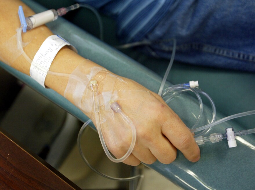 A person's hand rests on a chair with a plastic tube tapes to it.