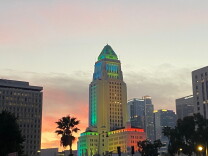City Hall is lit up at dusk next to the 101 freeway.