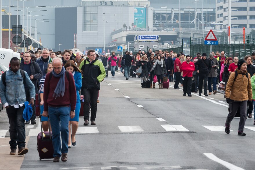 People walk away from Brussels airport after explosions rocked the facility in Brussels, Belgium Tuesday March 22, 2016.   Explosions rocked the Brussels airport and the subway system Tuesday, just days after the main suspect in the November Paris attacks was arrested in the city, police said. (AP Photo/Geert Vanden Wijngaert)