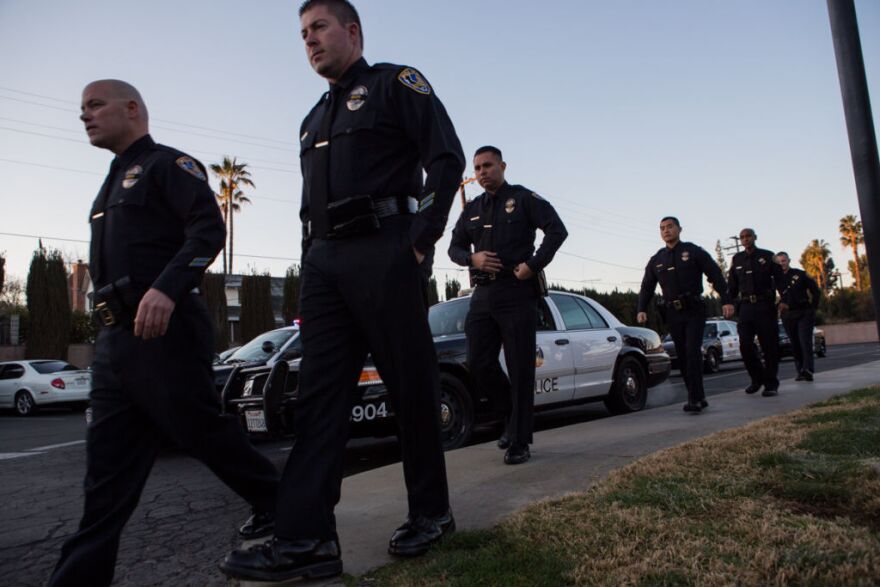 Riverside police officers walk towards the Acheson and Graham Mortuary, where a procession that includes multiple police agencies, veterans organizations, including the Patriot Guard Riders and the American Legion Riders, for Michael Crain will begin.

