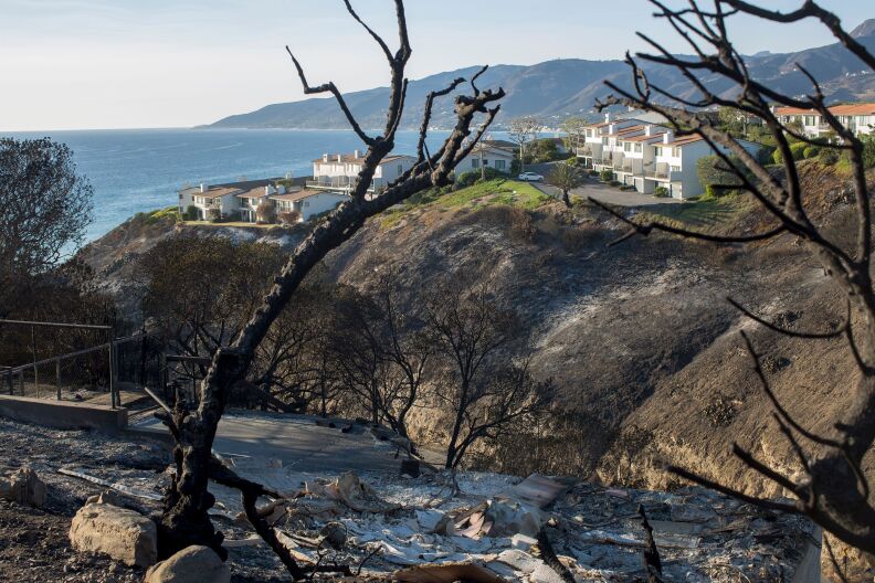 In the foreground, bare burned hills. In the background, Tows of untouched townhomes and the ocean.