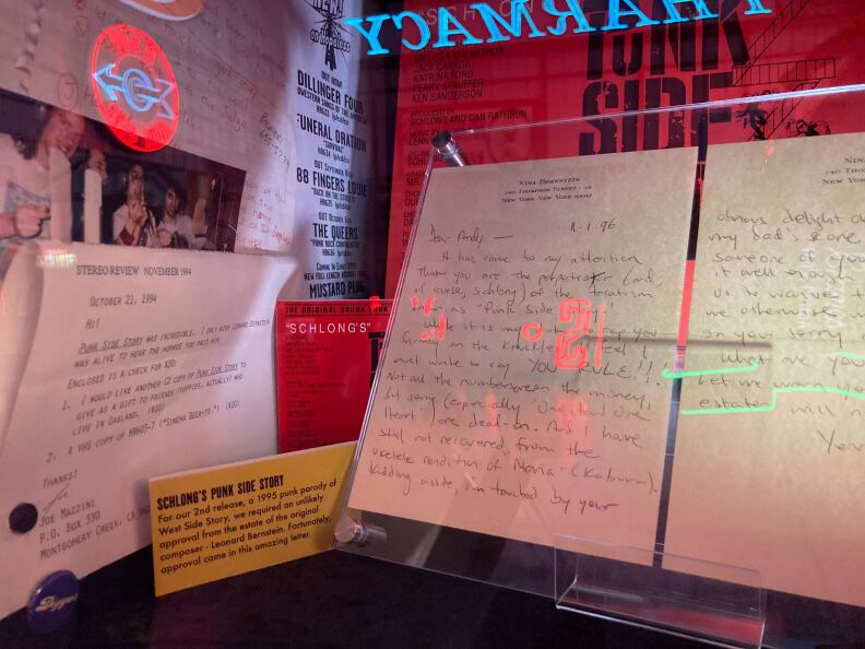 A close up of case full of different letters, signage and album covers from the Hopeless Records exhibit at the Valley Relics Museum, including a handwritten note on the letterhead of Nina Bernstein,  daughter of composer Leonard Bernstein, commending Hopeless Records for the punk version of the "West Side Story" soundtrack. 