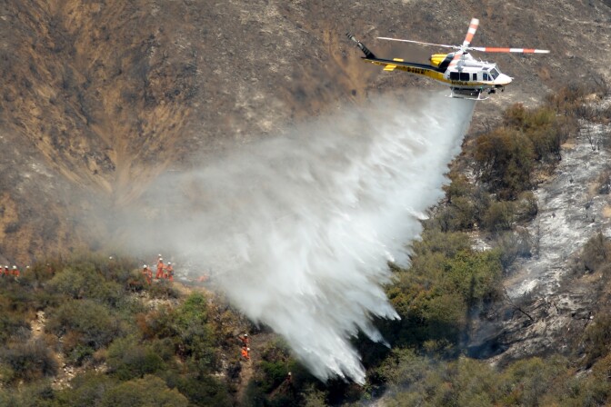 A Los Angeles County Fire Department helicopter drops water near an inmate hand crew cutting a containment line on a ridge at the Williams fire in the Angeles National Forest on September 4, 2012 north of Glendora, California. The fire began late September 2, putting an early end to Labor Day weekend camping and hiking for vacationers, who were evacuated from the area as it spread to more than 4,000 acres in size. Officials project that it will take at least another week to establish a containment line around the fire which is burning in rugged and difficult to reach backcountry.    