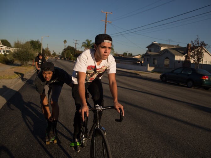 A friend of Damian pulls him on a skateboard through the streets of Pomona.