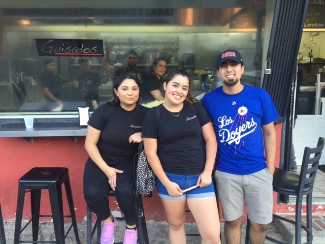 Outside Guisado's on Sunset Boulevard, (left-right) Leandra Reyes, Meghan Taylor Bravo, and Juan Lomeli watch the traffic heading into Dodger Stadium for Game 1 of the 2017 World Series.