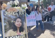 Six South Asian women and one woman stand next to a blown-up photo of a smiling Indian woman that reads "Justice for Moumita."