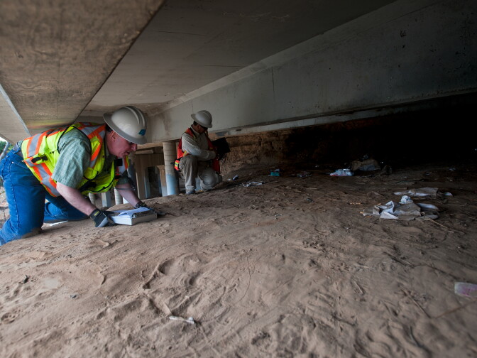 Jim Drago and Bing Wu inspect the bottom of the concrete structure. The bridge was widened in 1972.