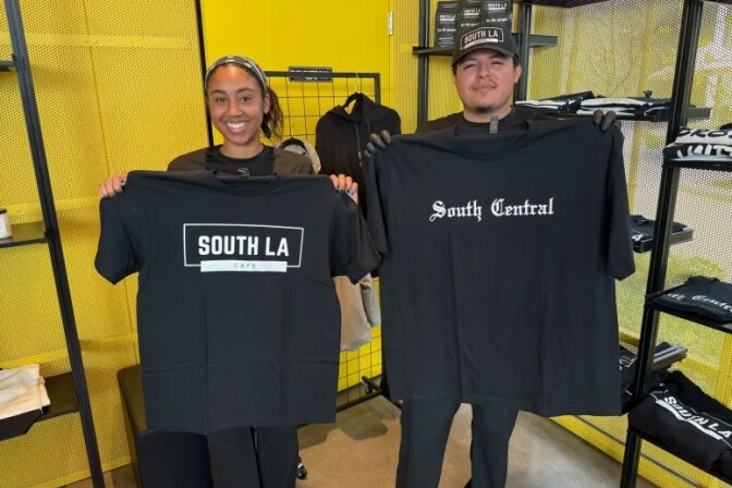 a woman holding a shirt that says "south la cafe" stands next to a man holding a shirt that says "south central"