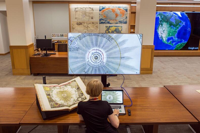 Deardra Fuzzell, a cartographic technology specialist at Stanford inspects a 1742 celestial atlas in both paper and digital form at the new David Rumsey Map Center. 