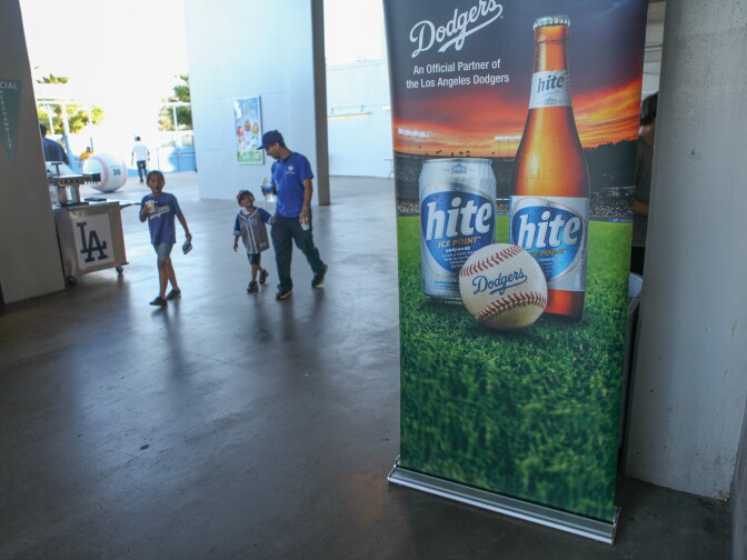 Dodger fans walk past a sign advertising the Korean beer Hite on the stadium promenade.