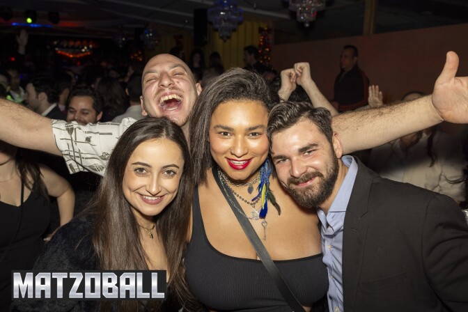 Four people - two women, two men - post for a camera during a party. 