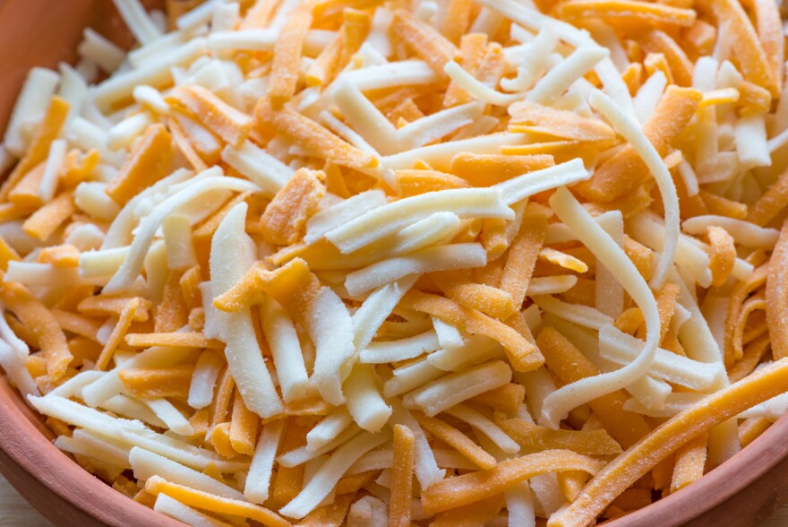 A close up of a bowl of several shreded cheese.