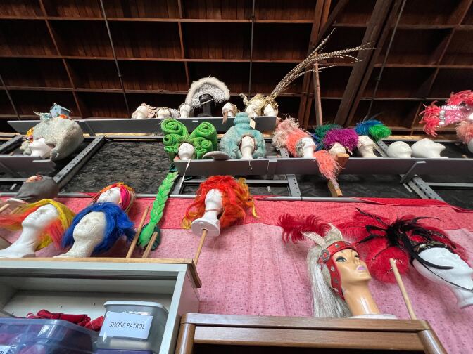 A wall of colorful wigs in a warehouse.