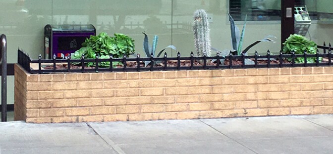 A wall by a plat bed that has pointed tops.