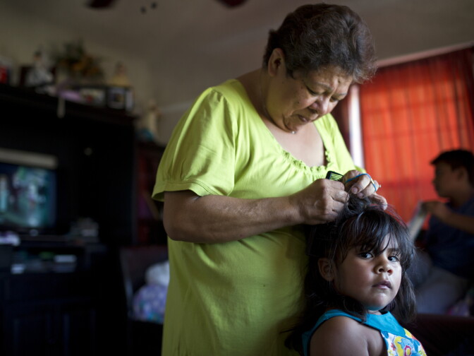 Maria Garcia, 58, braids her granddaughter's hair on Monday afternoon, August 3, 2015. Garcia took in her grandkids when her daughter landed in jail and couldn't care for her kids.