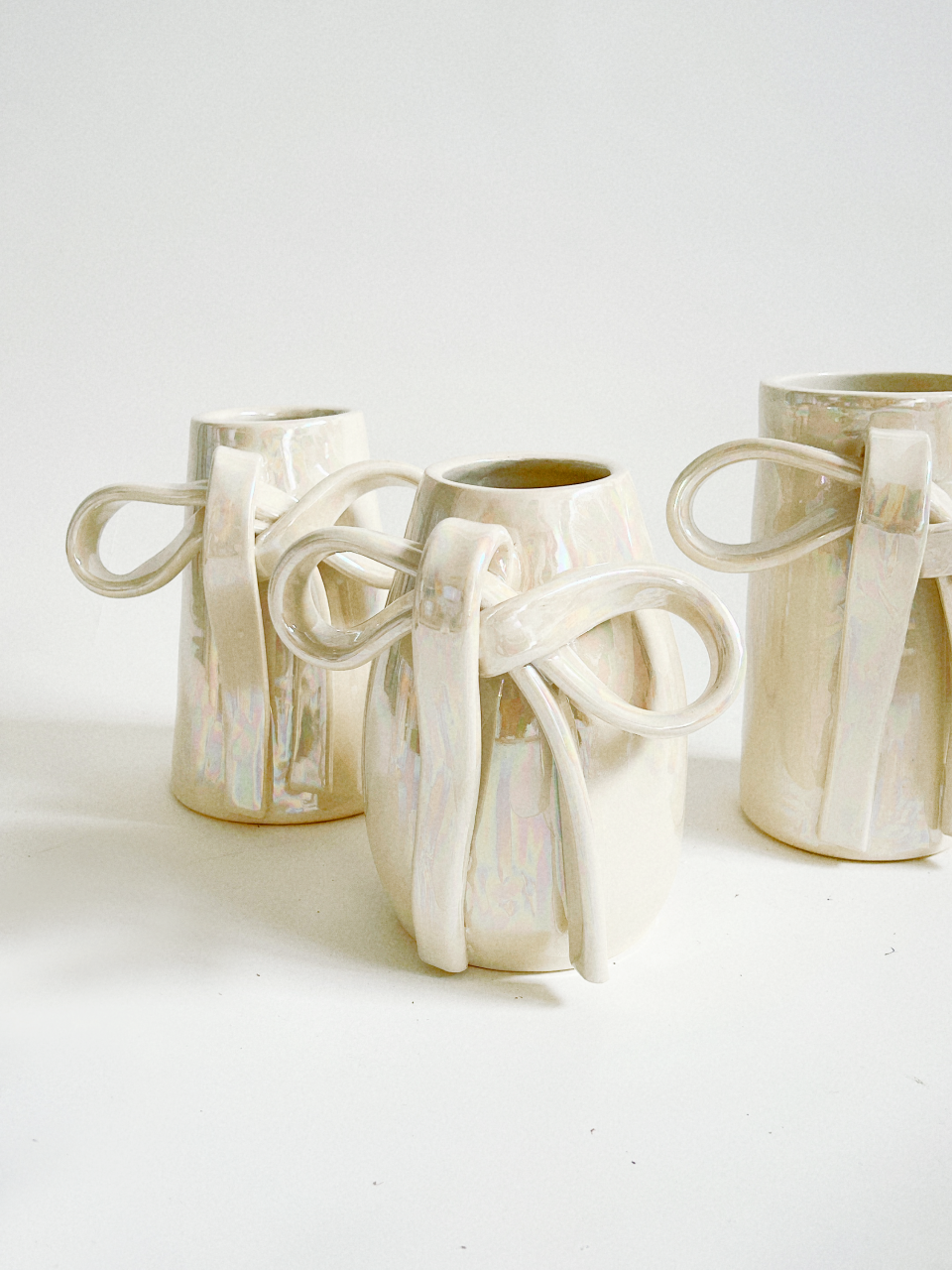 Vases in shades of off white have ceramic bows.