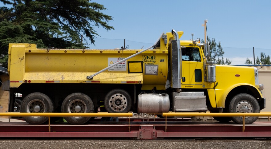 A yellow dump truck on a red platform. On the side of the truck is an Army Corps of Engineers label.