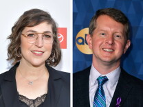 Side by side headshots of actress Mayim Bialik, a white woman with short brown hair wearing glasses, a black suit and a star of David necklace, and Jeopardy! winner Ken Jennings, a white man wearing a suit and tie. 