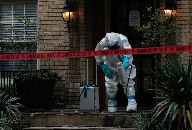 DALLAS, TX - OCTOBER 12:  A man dressed in protective hazmat clothing treats the front porch of an apartment where a second person diagnosed with the Ebola virus resides on October 12, 2014 in Dallas, Texas. A female nurse working at Texas Heath Presbyterian Hospital, the same facility that treated Thomas Eric Duncan, has tested positive for the virus. (Photo by Mike Stone/Getty Images)