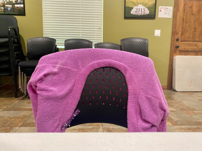 a chair with a pink cardigan belonging to Jami Taylor is draped over the back at a table in a room inside a drug treatment facility. 