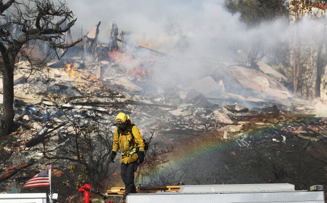 VENTURA, CA - DECEMBER 05: A firefighter works while battling flames from the Thomas Fire in a residential neighborhood on December 5, 2017 in Ventura, California. Around 45,000 acres have burned with 150 structures destroyed in the fire, forcing thousands to evacuate. (Photo by Mario Tama/Getty Images)