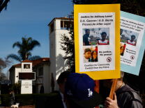 Protesters hold signs calling for justice for Anthony Lowe asking DA Gascòn and AG Bonta to "prosecute cop killers." Photos of Lows are attached to colorful poster boards.