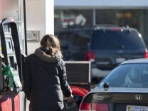 A woman fills her car with gas in Woodbridge, Va., on Tuesday. Supplies of crude oil and refined gasoline have driven prices at the pump down, and they're  expected to go even lower.