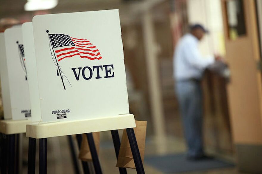 Voting stations are concealed with white barriers that read VOTE on the outside with an image of an American flag.