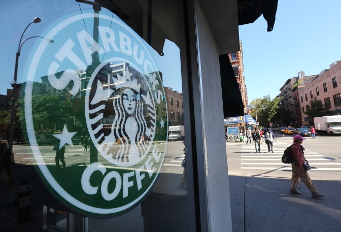 NEW YORK, NY - SEPTEMBER 18:  A woman walks past a Starbucks cafe in Manhattan on September 18, 2013 in New York City. Starbucks announced it will no longer welcome guns inside its cafes following the Washington Navy Yard shootings which left 13 dead.  (Photo by Mario Tama/Getty Images)