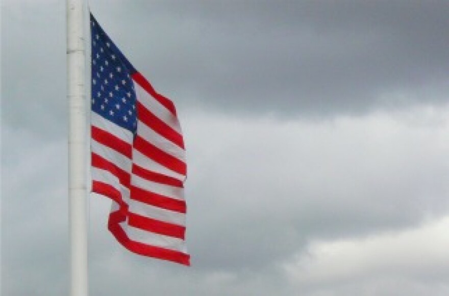 An American flag flies in a cloudy sky.