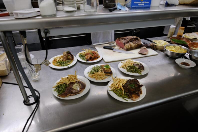 6 dishes sit on a metal countertop in a professional kitchen