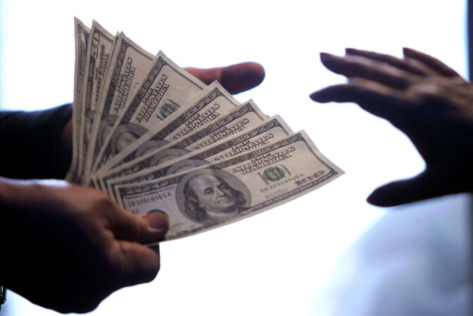 United States Dollar notes exchange hands at a local bank in Beijing 15 May 2006.  China set its parity rate for the yuan at 8.0150 to the US dollar, one day after it allowed it to rise and break through the psychologically important 8.000 mark.                AFP PHOTO (Photo credit should read STR/AFP/Getty Images)