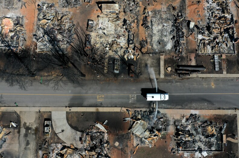 In an aerial view, a water truck sprays water on the remains homes and businesses that were destroyed by the Dixie Fire.