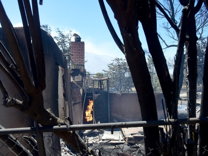 A fire continues burning amid the rubble of a demolished home in the community of Squirrel Valley in Lake Isabella, California on June 24, 2016.