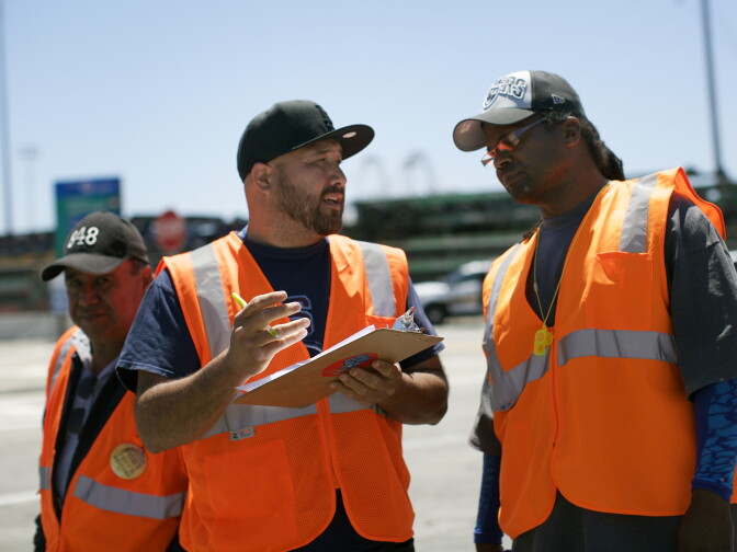 Said Benavides, left, of Teamsters Local 848 and Malik Shakur, a Teamsters organizer, track trucks from four companies coming in and out of the Port of Long Beach on Monday morning, April 27, 2015. Independent truckers for four companies have gone on strike, asking the four employers to reclassify them as permanent employees so that they can join the Teamsters union.