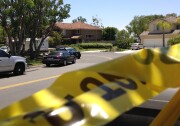 Police tape closes a street where four people were found dead in a home, center, on Tuesday, May 27, 2014 in suburban Mission Viejo.